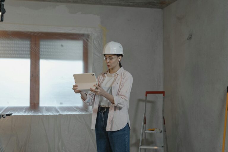 Woman in hard hat using tablet for construction project in unfinished interior.